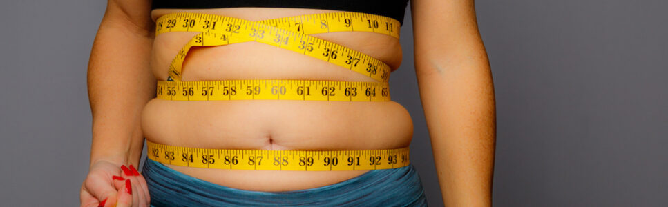 Woman in Active Wear With Squeezed Measuring Tape on a Gray Background Ayurvedic Treatment For Cholesterol in sydney